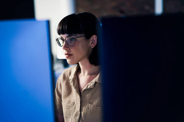 Concentrating, serious and night with woman and computer for software engineering, developer and designer. Cyber security, data science and code with employee in office for neon, website and html stock photo
