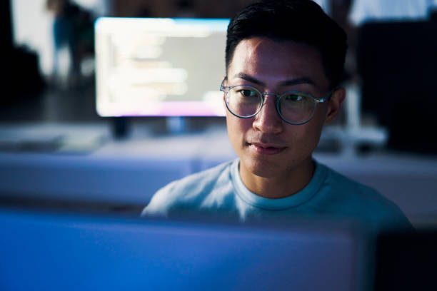 Computer coding, programming and asian man in cybersecurity, software development and html script. Night person from china with information technology career, database code and monitor network safety stock photo