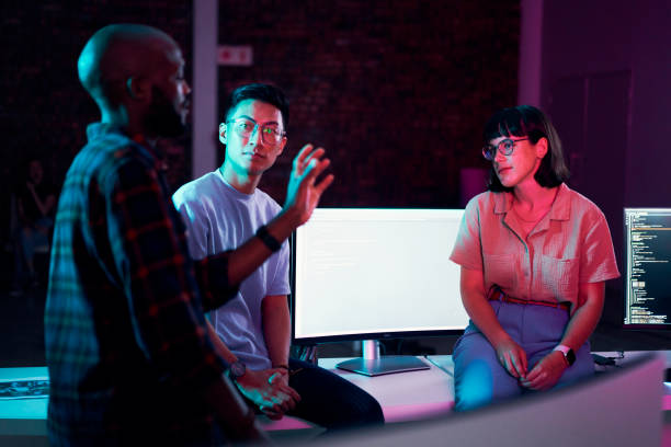 istock Business people, talking or planning teamwork in night office of software development, cybersecurity or database safety. Programmer, developer or engineer on neon technology for coding diversity idea 1469706478