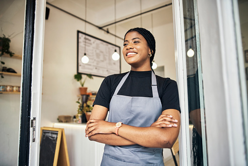 Happy, smile and open with black woman in coffee shop for small business owner, retail and management. Bakery, restaurant and cafe with girl employee at door for welcome, waitress and  empowerment