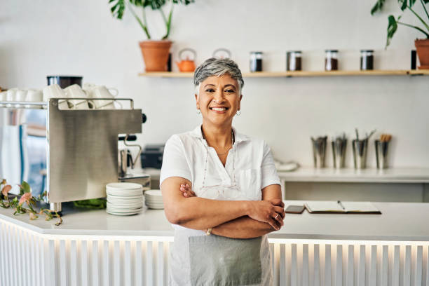 Happy, portrait and senior woman in coffee shop for small business owner, retail and management. Bakery, restaurant and leadership with employee in cafe for welcome, waitress and empowerment stock photo