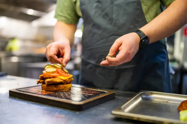 chef hand cooking chickenburger on restaurant kitchen