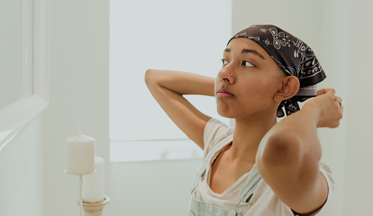 Wide image of a girl tying bandana in front of the mirror