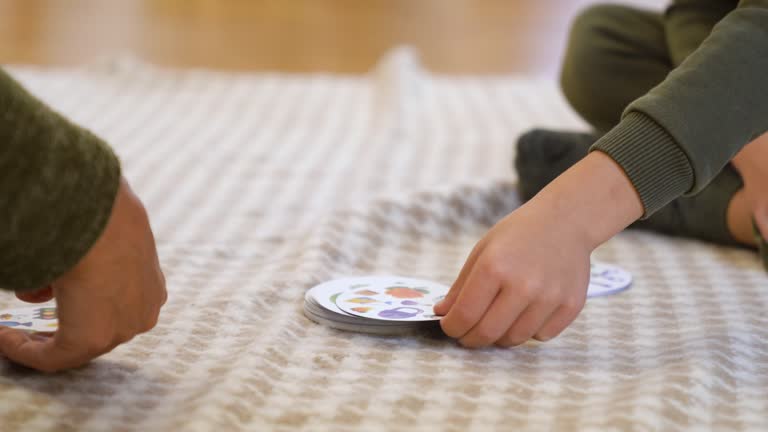 Preschool boy laughing and playing board game with grandmother at the floor