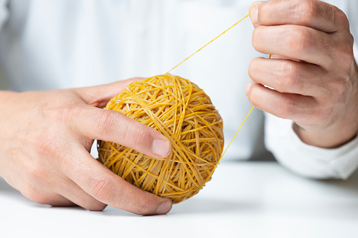 Business man is pulling rubber band ball. Close-up.