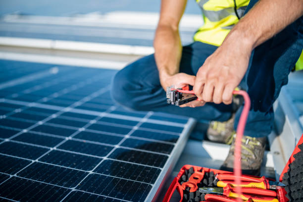 hombre usando alicates para cortar cable en paneles solares. - alicates fotografías e imágenes de stock