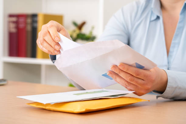 woman putting a letter inside an envelope at office Close up of woman hands putting a letter inside an envelope on a desk at home or office mail stock pictures, royalty-free photos & images