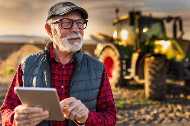 istock Senior farmer with tablet in field with tractor in background 1469735228