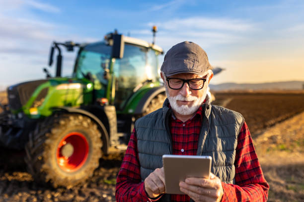 istock Senior farmer with tablet in field with tractor in background 1469735234