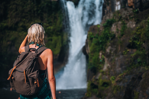 Woman looking at a scenic view of a waterfall in Bali, Indonesia. 
Tropical forest and waterfall.