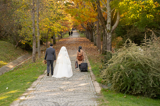 Bride groom walking on forest path and muslim girl carrying her belongings with bag.