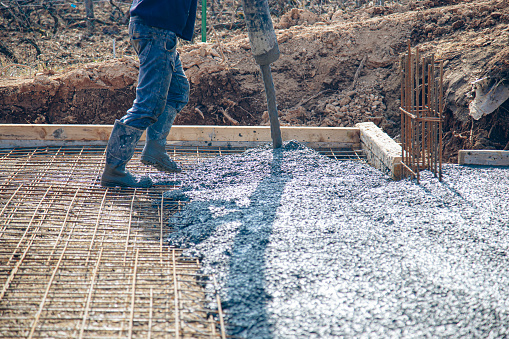 Worker installing concrete in preset reinforcement bar mesh on a new building development