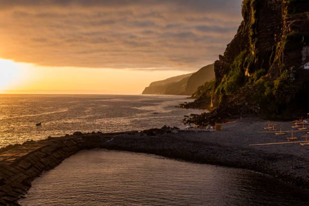 sunset over the atlantic ocean with the bay and the rocks , photographed from the rocks of the bay of Porto do Sol in Madeira Portugal