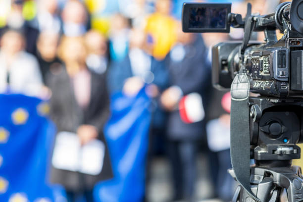 Filming political meeting or publicity event with television camera, European Union flag in background stock photo