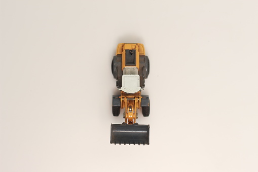 a close up of miniature orange wheel loader toy isolated on white background. concept photo of heavy equipment miniature toy.