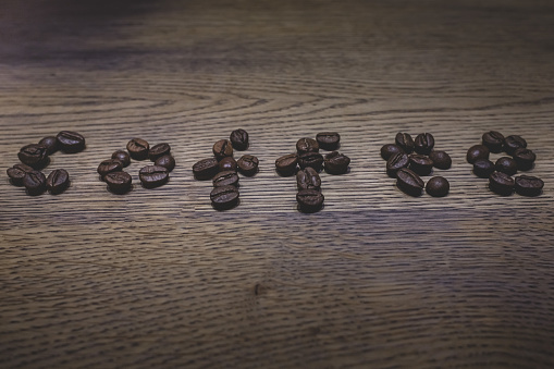 The word coffee. Coffee beans on the table. Roasted coffee. Inscription made of food. Wooden background.