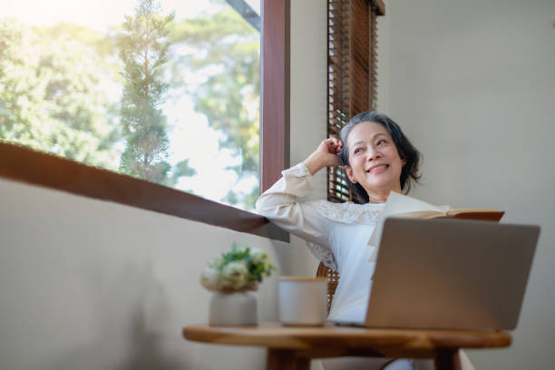 istock Elderly women sit and relax, stressed, watching series on laptops, reading and taking notes in notebooks and sipping tea happily inside the house with the brightest light and fresh air. 1469754670