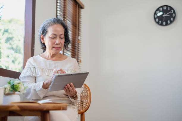 istock Elderly women sit and relax, stressed, watching series on laptops, reading and taking notes in notebooks and sipping tea happily inside the house with the brightest light and fresh air. 1469755074