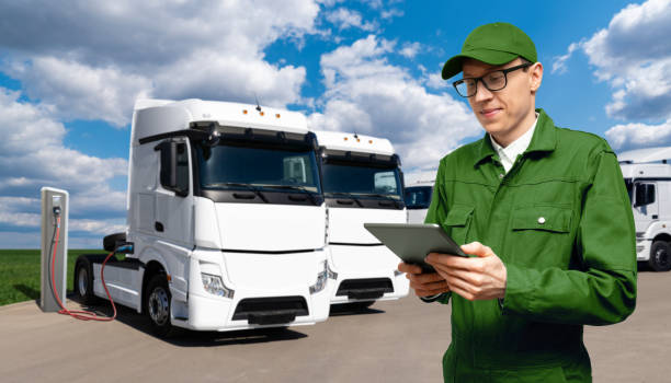 istock Fleet manager with a digital tablet stands next to electric trucks 1469756351