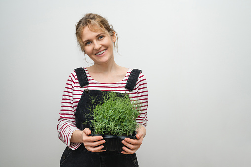 A woman is holding a micro green in her hands.