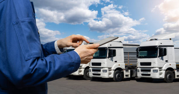 istock Manager with a digital tablet on the background of trucks 1469758148
