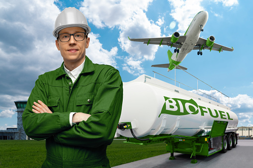 Engineer on a background of airplane and biofuel tank trailer. New energy sources