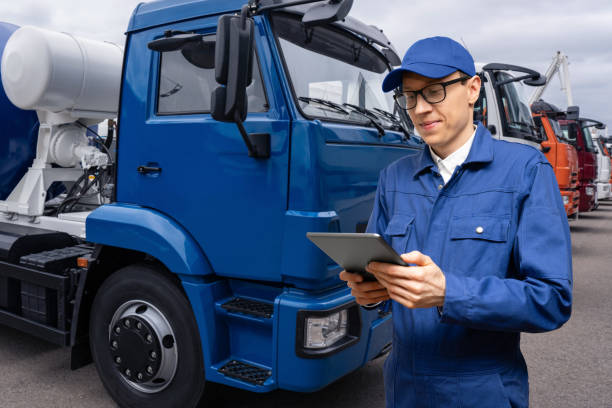 istock Manager with a digital tablet on the background of trucks 1469759529