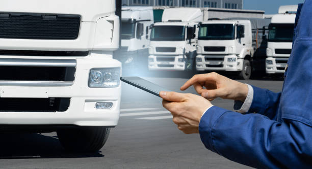 istock Manager with a digital tablet on the background of trucks 1469759597