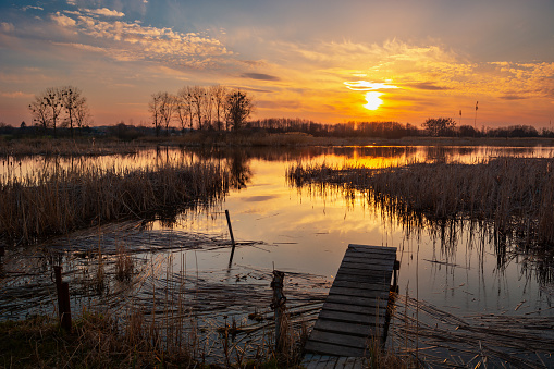 A small wooden pier on the lake shore with sunset, spring view, eastern Poland