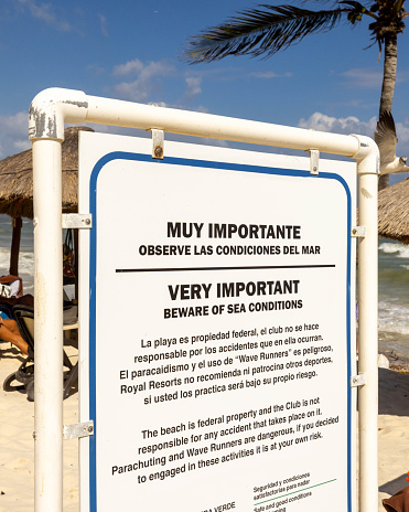 A sign in Spanish and English warning beachgoers to be cautious in the ocean