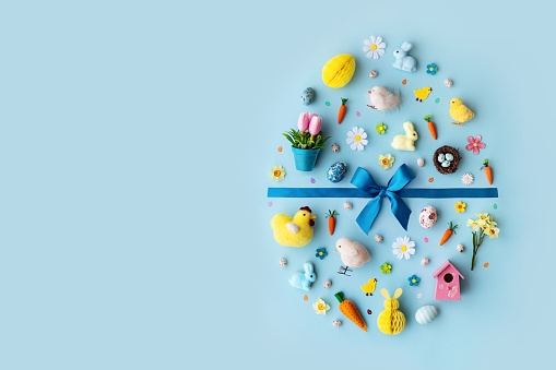 Collection of Easter objects laid out in an Easter egg shape, overhead view, flat lay