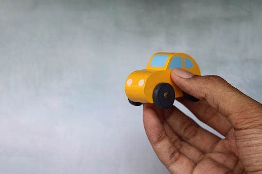 Closeup image of hand holding toy car with copy space. Transportation concept