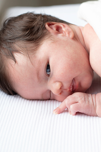 High angle above view of  newborn baby on white sheet.