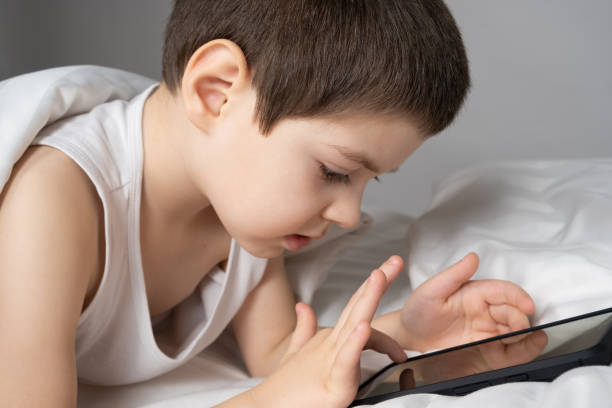 istock A 5 year old boy plays games on his phone while lying in bed. Gadgets in bed before bedtime in a child 1469773158
