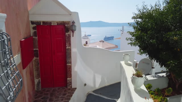 Traditional Greek architecture with a bright red door and a view of the blue sea. Santorini, Cyclades, Greece