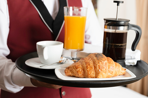 Room service is bringing breakfast with orange juice, croissant and french press coffee.