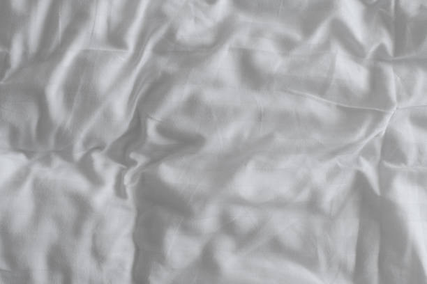 istock Texture of crumpled white bed sheets as background, top view 1469776222