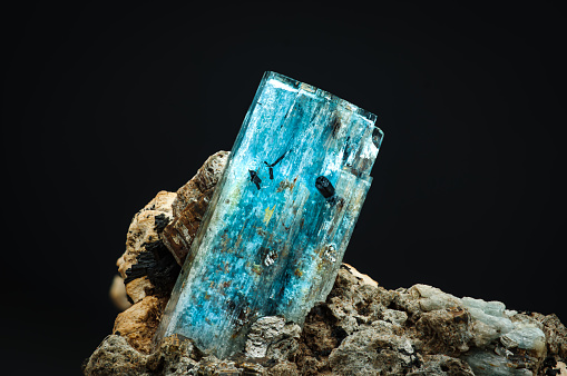 blue aquamarine with schorl (black tourmaline inclusion. macro detail texture background. close-up raw rough unpolished semi-precious gemstone