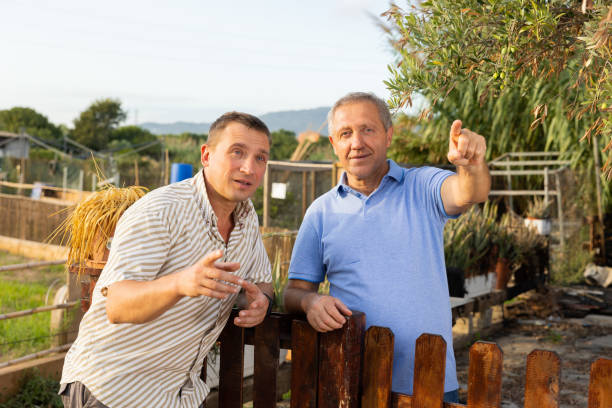 istock Two men neighbors standing at fence and chatting 1469782470