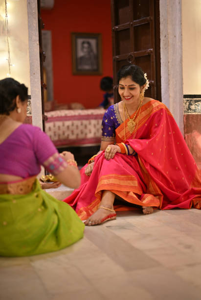 istock Indian Woman in sari applying Alta (red dye) on other woman's feet during a traditional function 1469785048