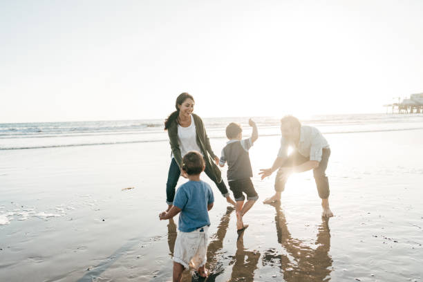 parents playing with kids on the beach - spring break imagens e fotografias de stock