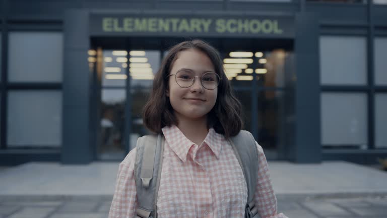 Portrait smiling girl standing at school entrance. Teenager looking camera.