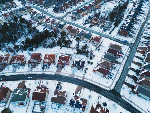 Car has left snowy winter tire tracks leaving a suburban house from the driveway out onto the street. February winter scene near Rochester, New York State.