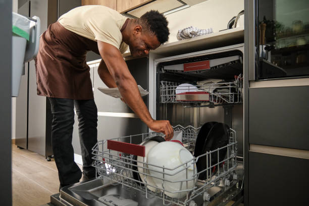 Young black man putting dishes in the dishwasher.