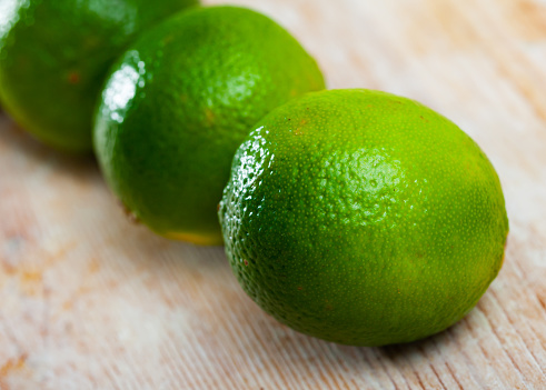 Closeup of whole ripe green limes on wooden table. Vitamin fruits