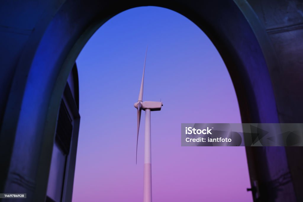 Open the door to the wind turbine, in a purple and blue twilight. Open the door to the wind turbine, in a purple and blue twilight. Renewable energy concept. Sustainable Resources Stock Photo