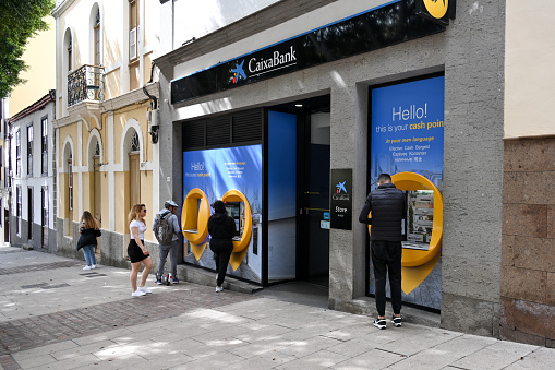 Adeje, Teniffa, Spain - February 11, 2023 - Unidentified customers at CaixaBank ATMs in the town of Adeje on the island of Tenerife.