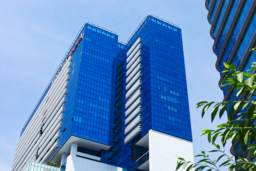 view of a contemporary glass skyscraper reflecting the blue sky