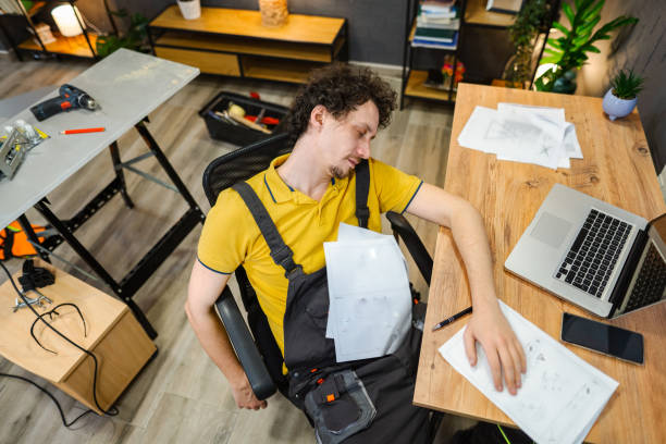 istock Craftsman falling asleep sitting on a chair while reading instruction manual 1469787276