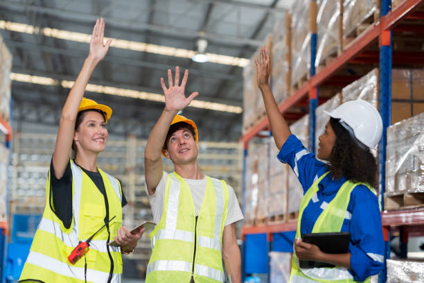 istock Group of warehouse workers raising hands together at the storage warehouse. Complete finish job. Successful of work concept 1469787427